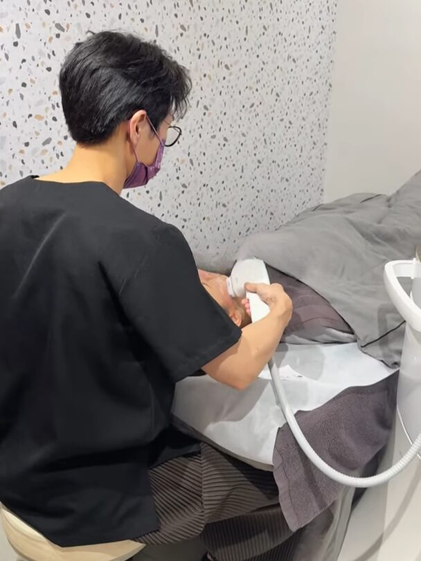 暖男醫師正在為患者進行臉部微整療程,使用儀器操作中。
