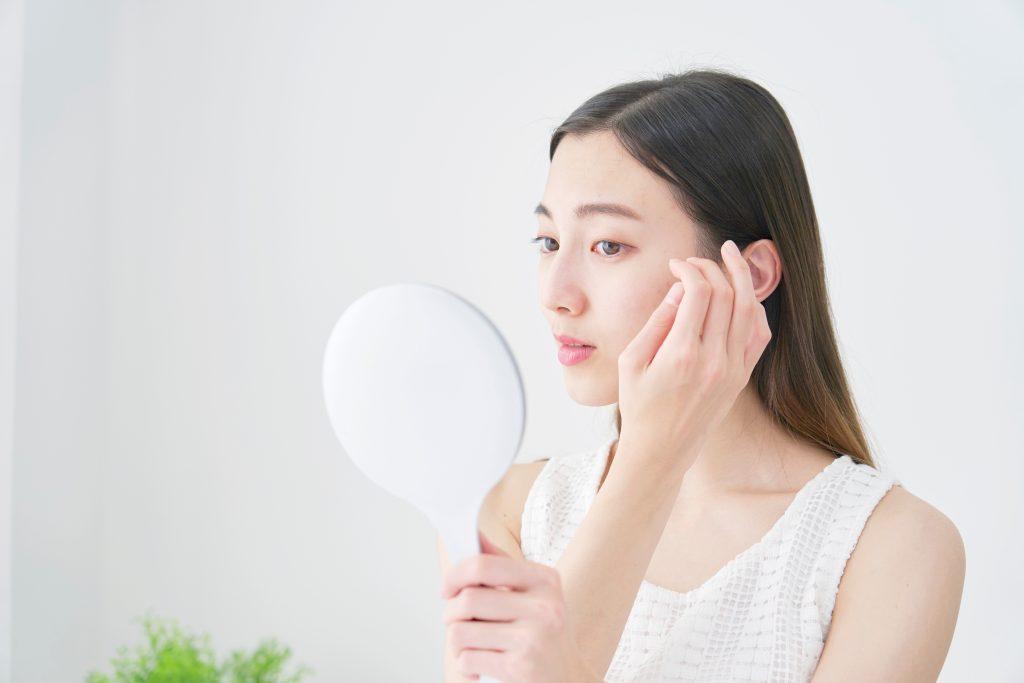 女人用手鏡檢查自己的臉。