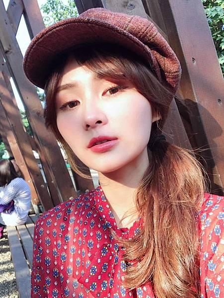 年輕女子,有著適合秋天的妝容和髮型,穿著紅色圖案襯衫和棕色報童帽。